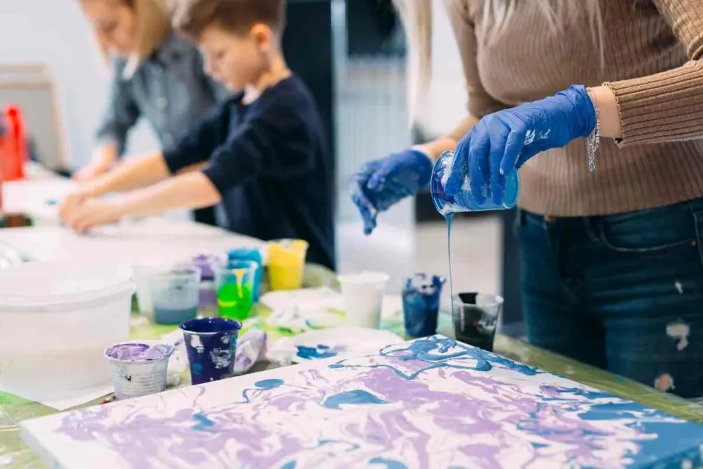 Demonstrating clean pour paint pouring technique with blue and purple paints