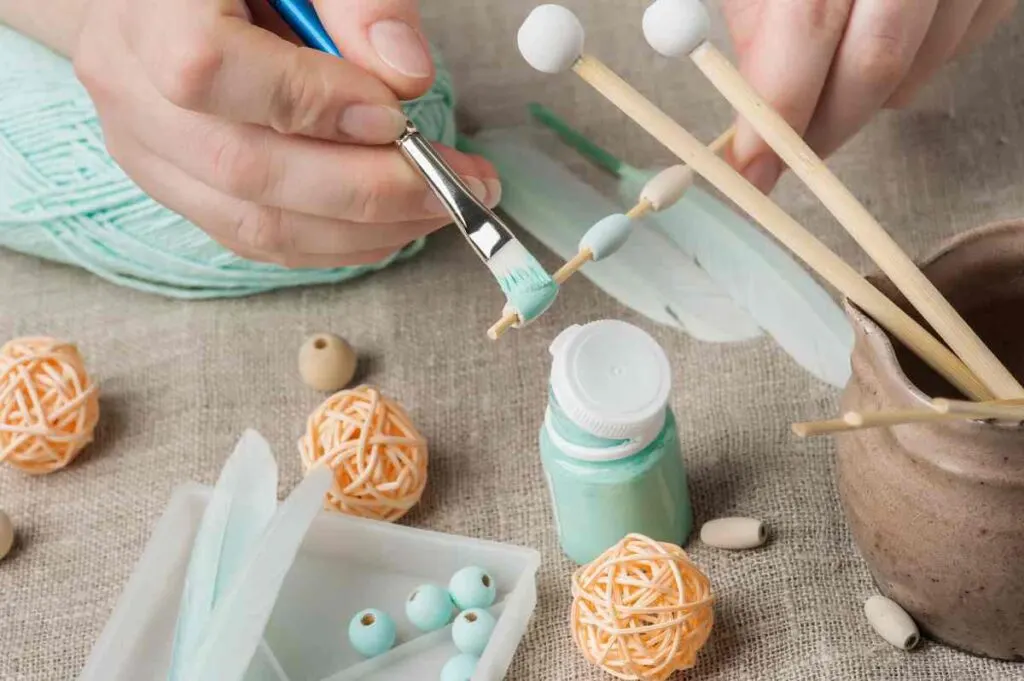 Close up of woman using the best paint for wood crafts to paint wooden beads teal
