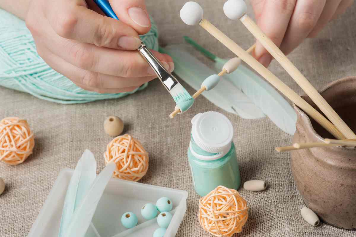 Close up of woman using the best paint for wood crafts to paint wooden beads teal