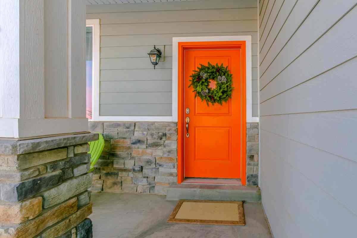 Orange front door with green wreath is a great option for door decorating ideas