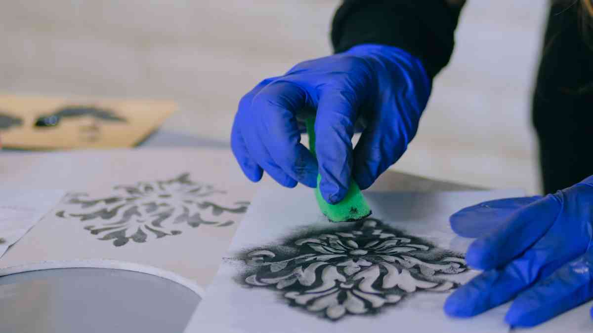 Using a sponge and black paint to paint stencils for walls