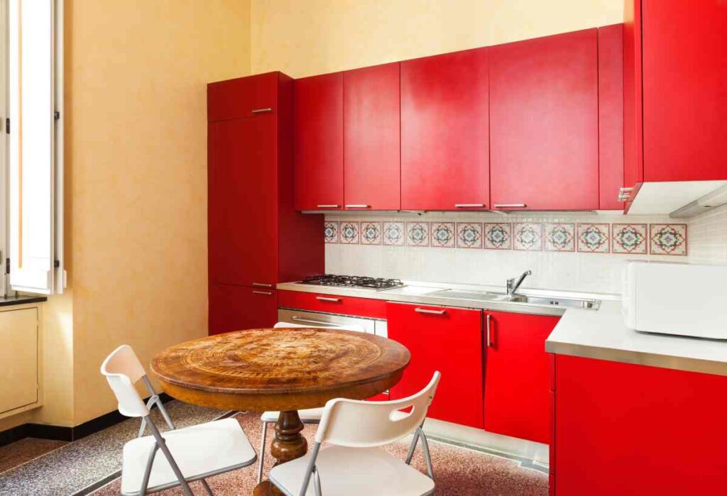 Kitchen cabinets painted red with white counter and backsplash