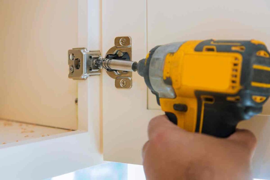 Using a drill to remove cabinet doors before distressing