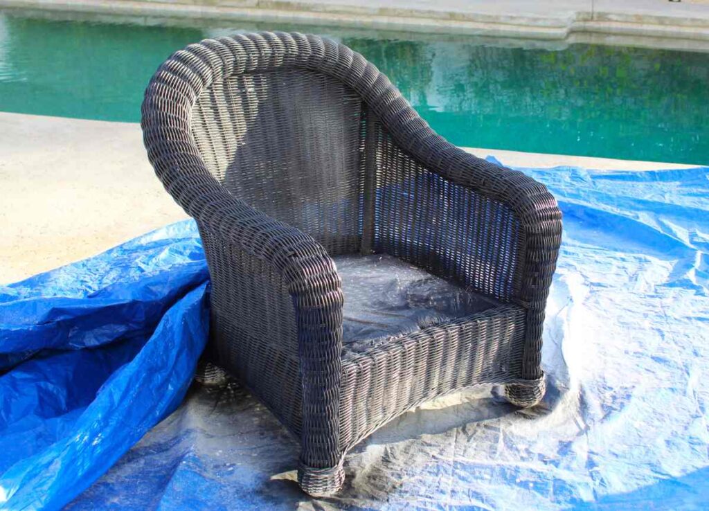 Wicker patio chair in the process of being painted black