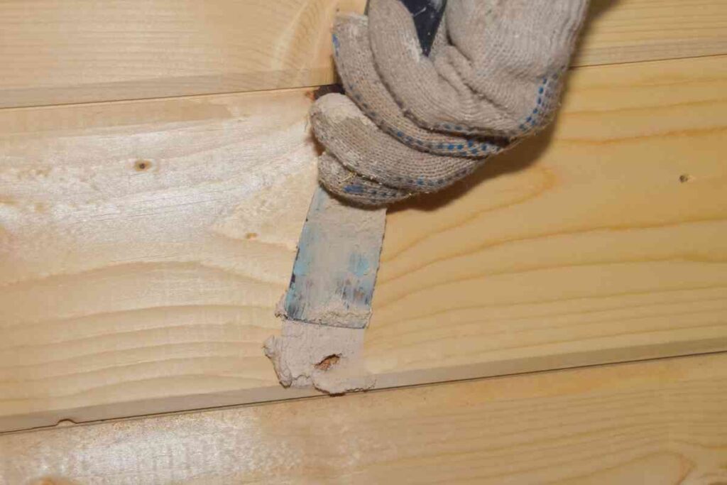Using a putty knife to apply wood filler to veneer furniture