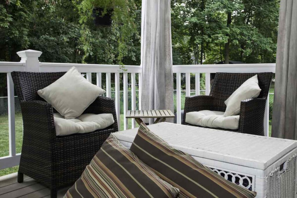 Wicker patio chairs with throw pillows and striped rug