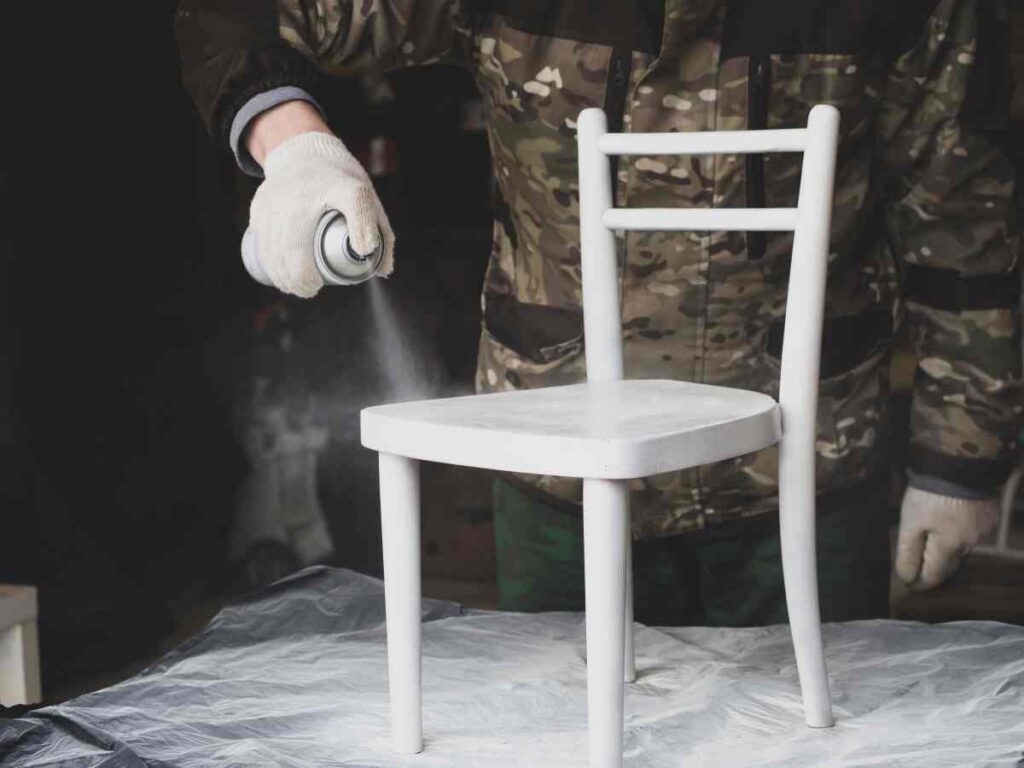 Man spray painting furniture a white chair