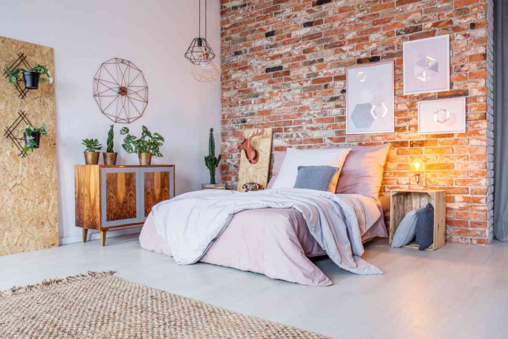 Bedroom with a brick wall, white spread, pictures, and knick knacks