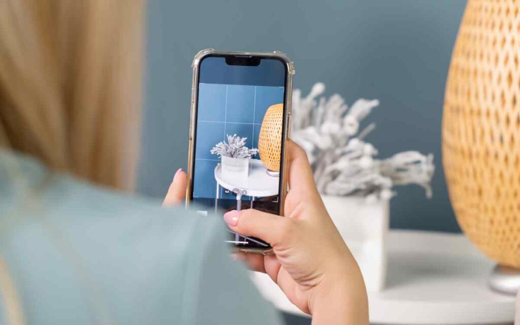 Woman using a mobile phone to take pictures of a table for resale