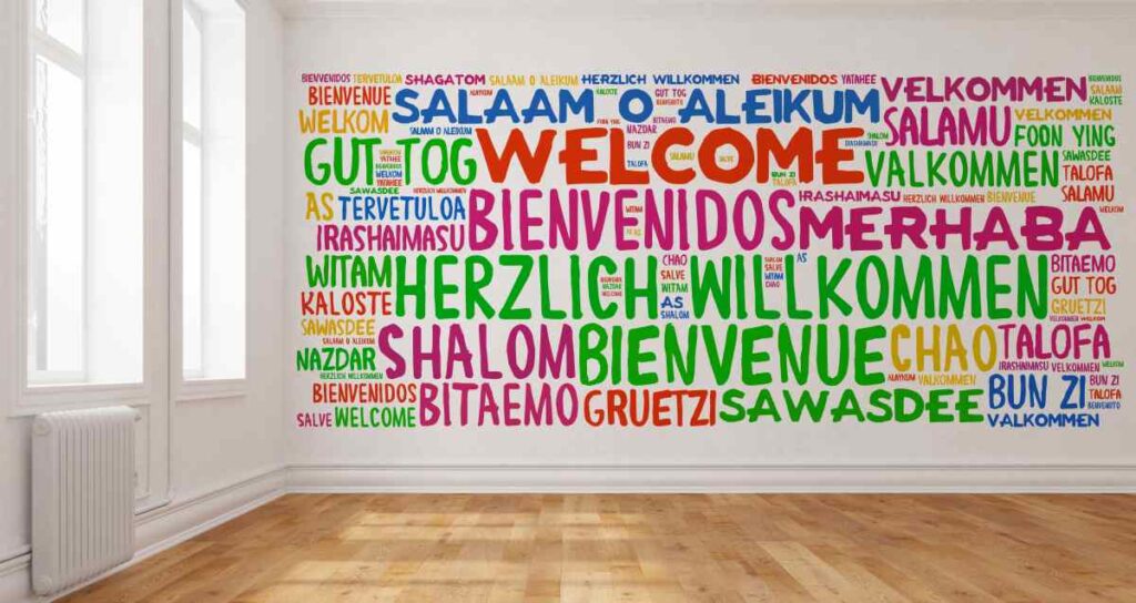 Wall stenciled with WELCOME in several languages and colors