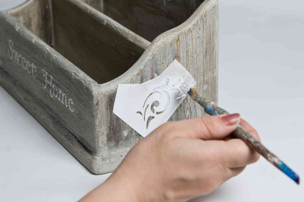 Painting a stencil design on a wooden box
