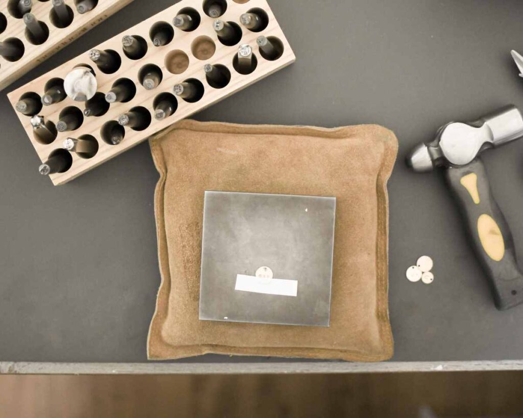 Jewelry block, ball peen hammer, and stamps used to make stamped metal jewelry
