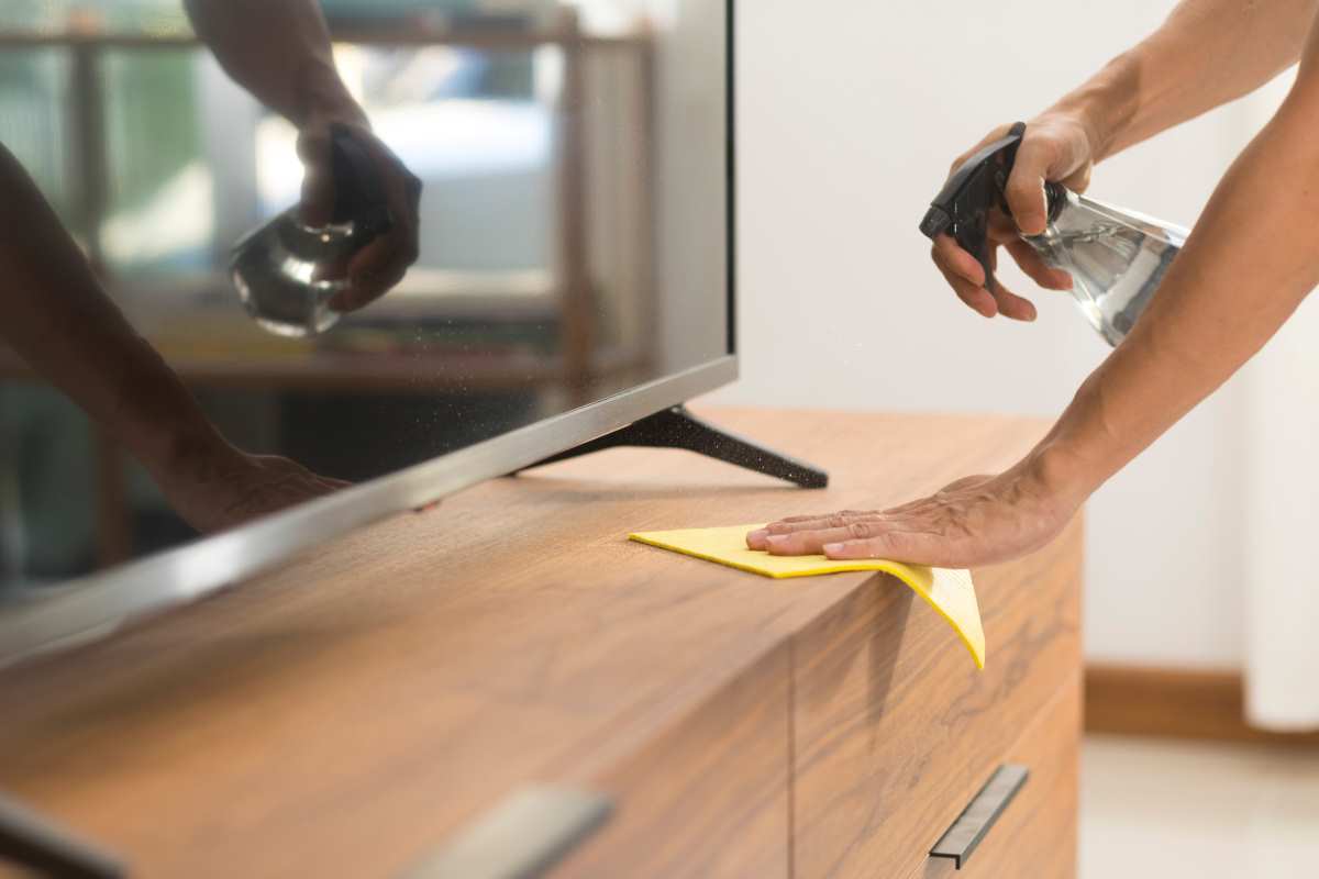 A person using a cloth and cleaner, one method for how to clean wood furniture