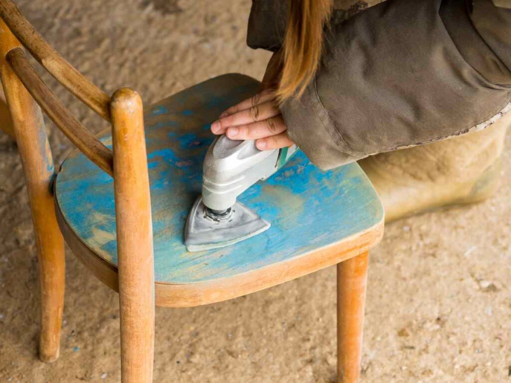 An old blue chair is getting sanding as a step for refinishing furniture