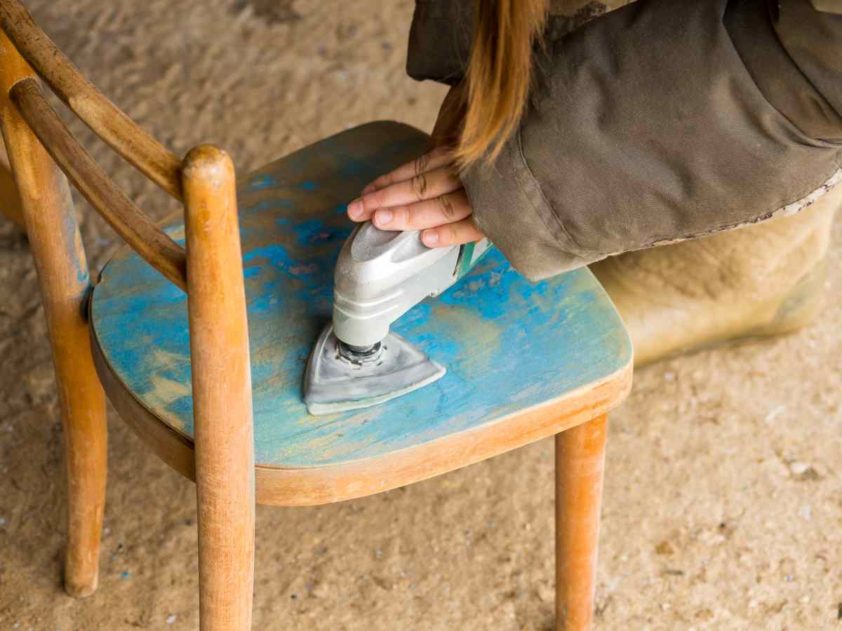 An old blue chair is getting sanding as a step for refinishing furniture