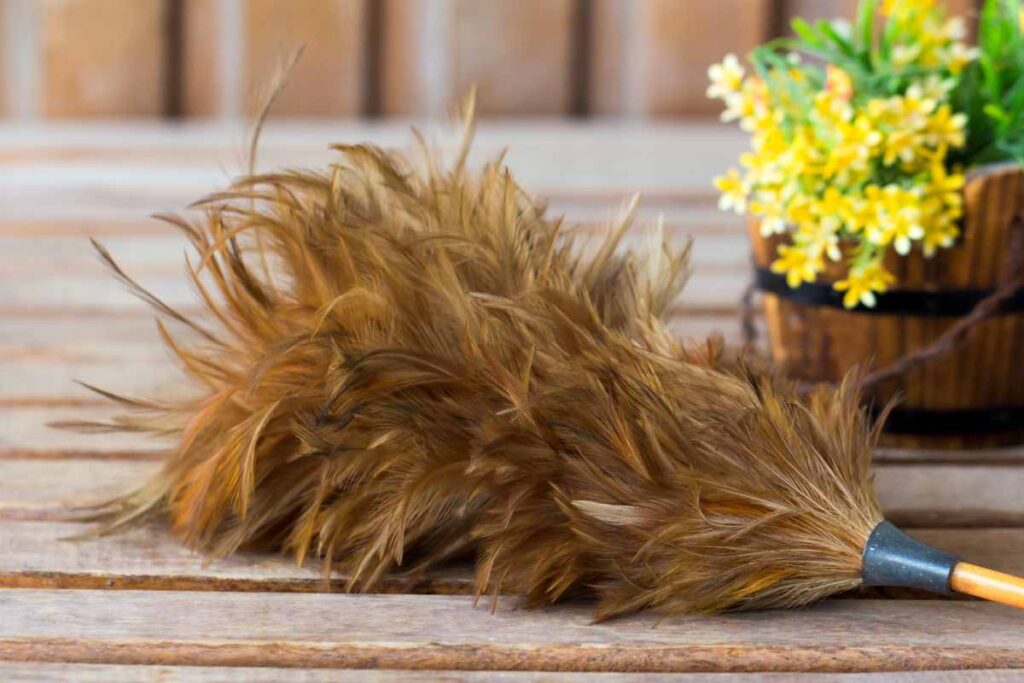 Feather duster on a wooden table with a basket of yellow flowers