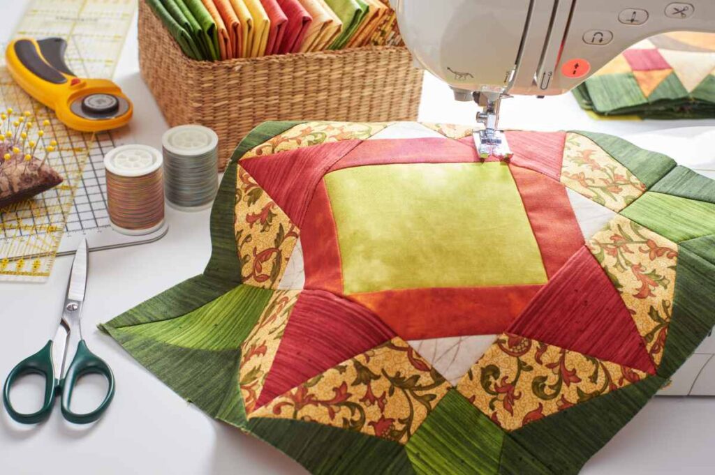 Green, orange, and yellow patchwork quilt block being sewn on a machine