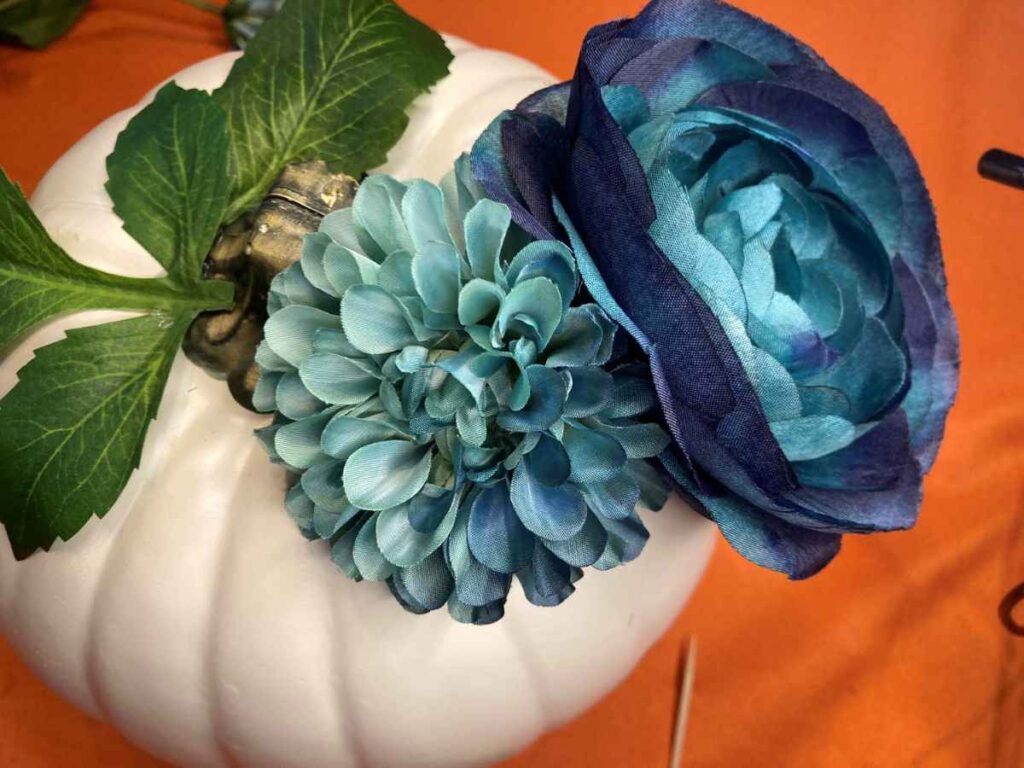 Blue flowers glued to a white pumpkin
