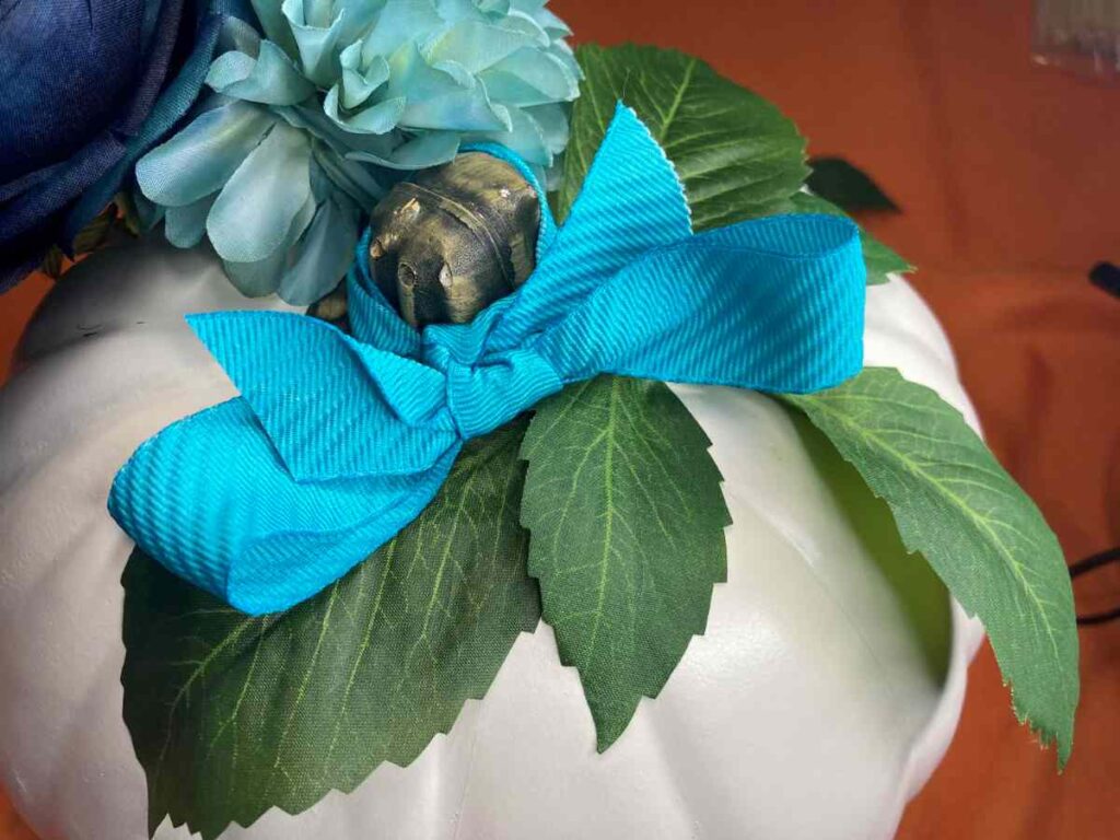 Blue ribbon and flowers added to a white pumpkin
