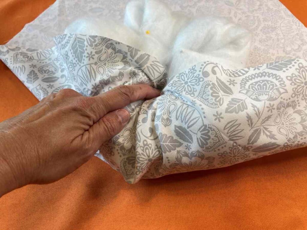 Wrapping fabric around a roll of batting to make a pumpkin