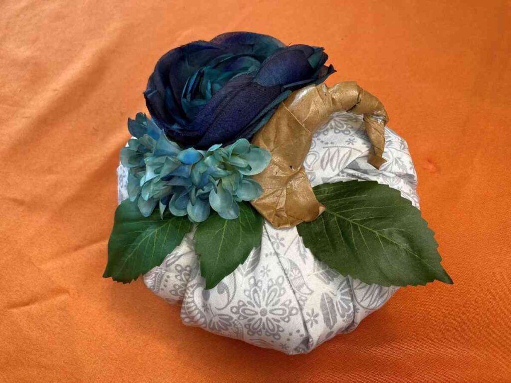 Completed grey and white fabric pumpkin with blue flowers and greenery