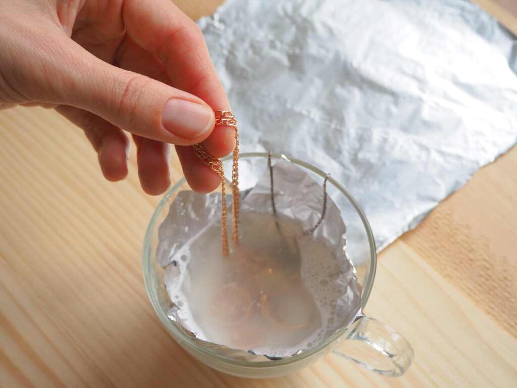 Using salt and aluminum foil in a cup of water as a method for how to clean metal jewelry