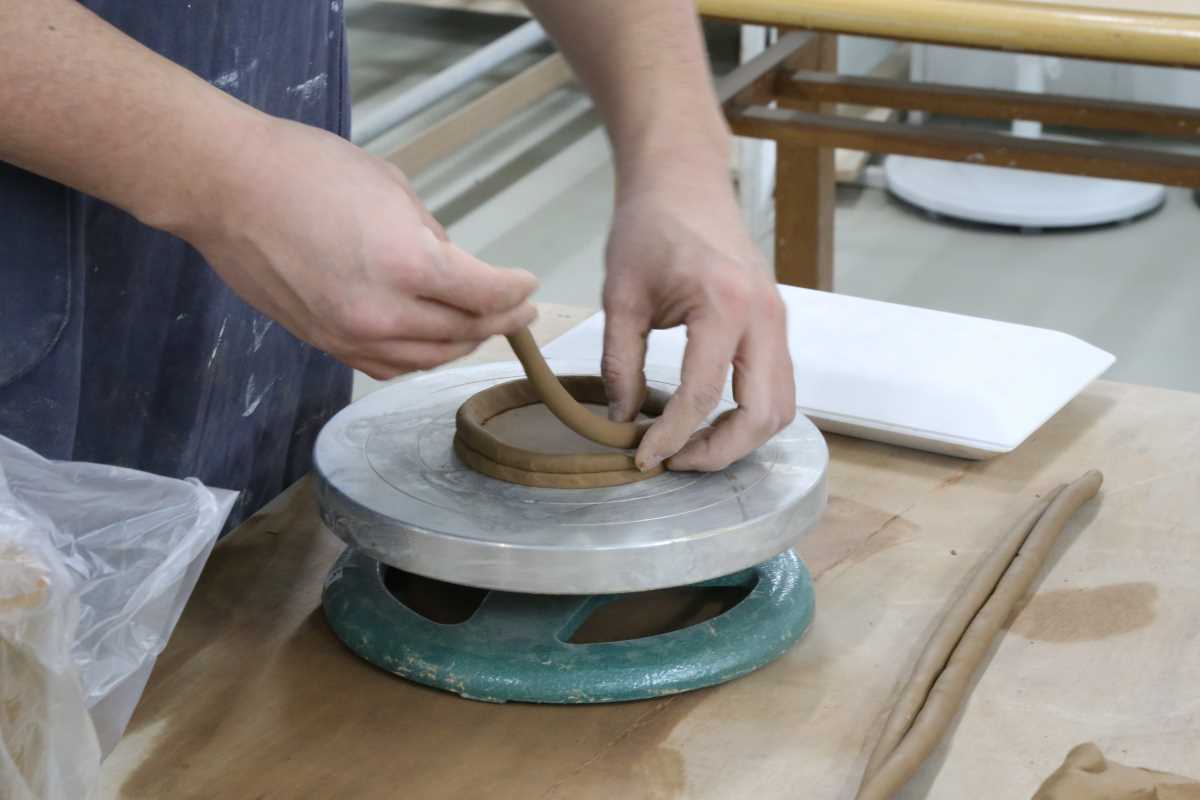 A person making a pot out of pottery coils, one of many beginner pottery ideas