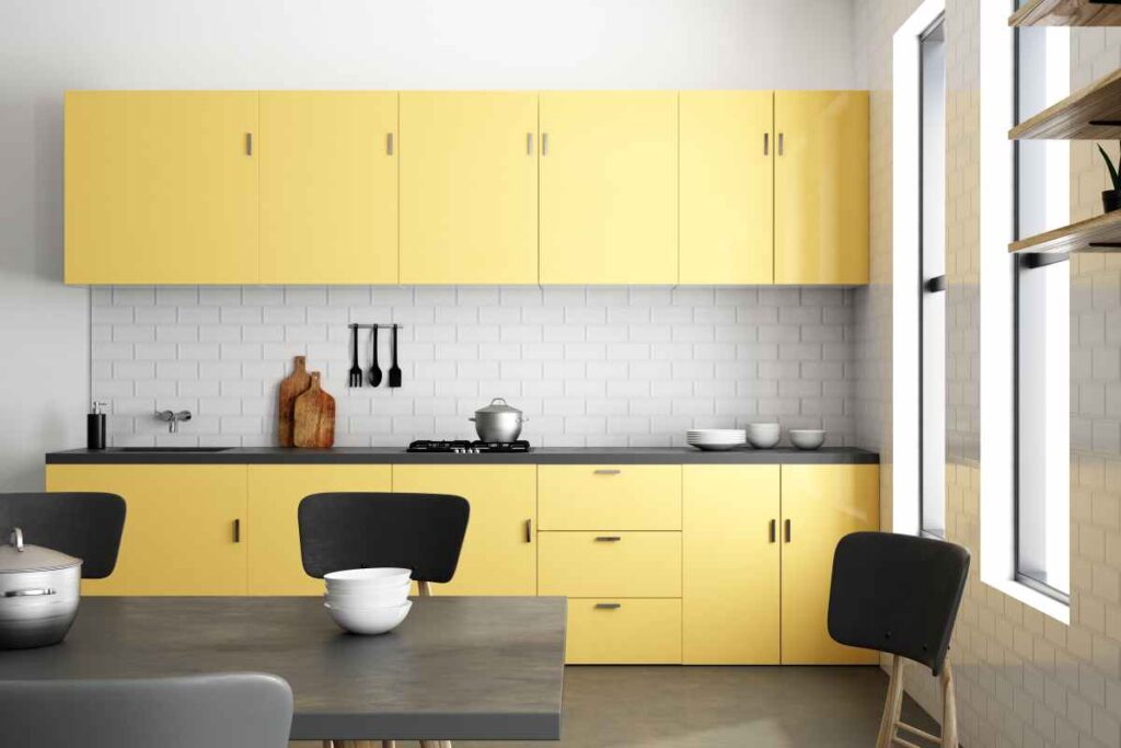Yellow kitchen cabinets with a grey table and black chairs