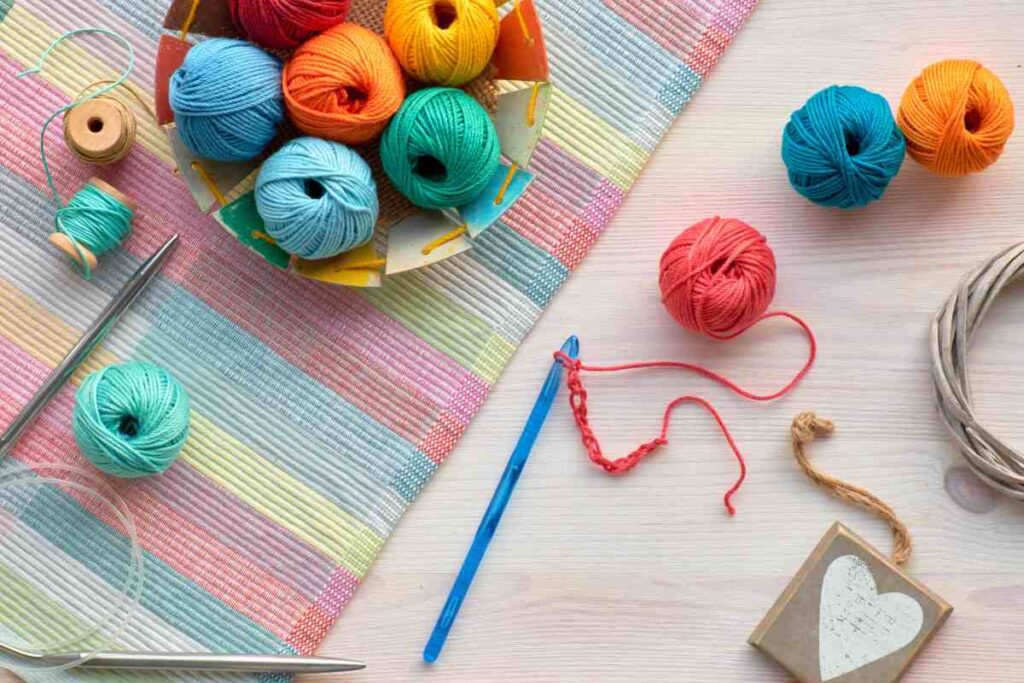 Skeins of colorful yarn, crochet hook, and a mat