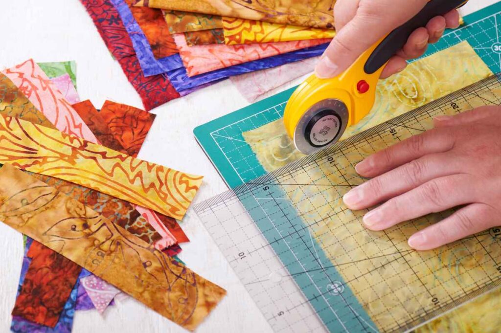 A person using the best rotary cutter for quilting to cut fabric squares