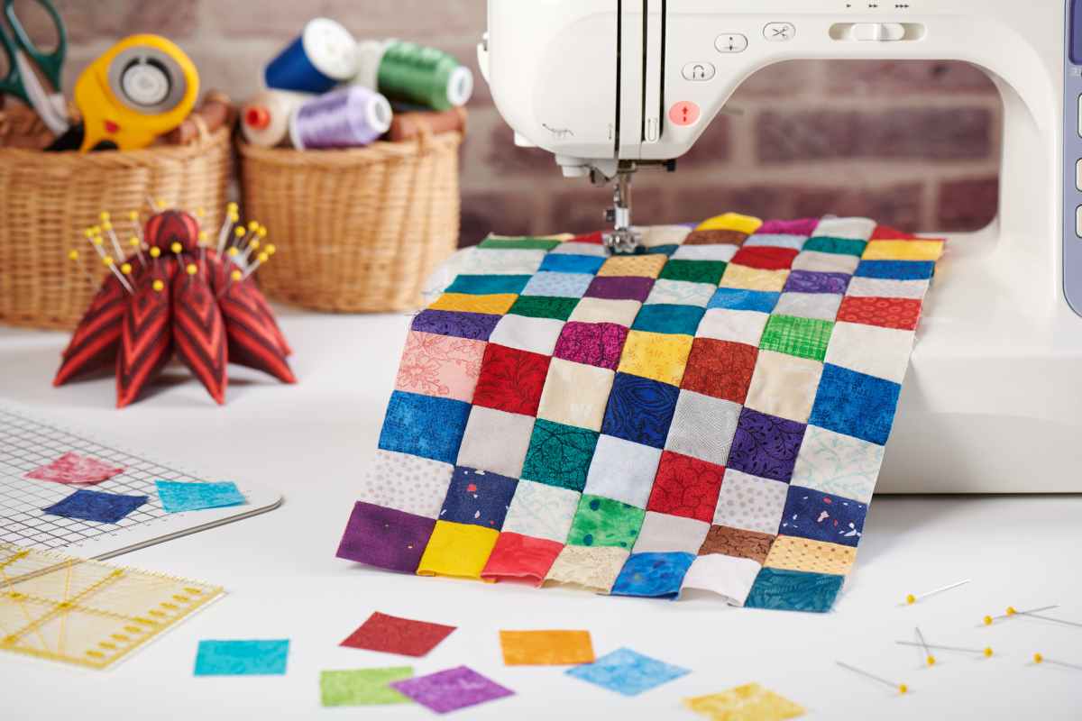 Finished quilt block with a sewing machine, thread and other quilting supplies for beginners