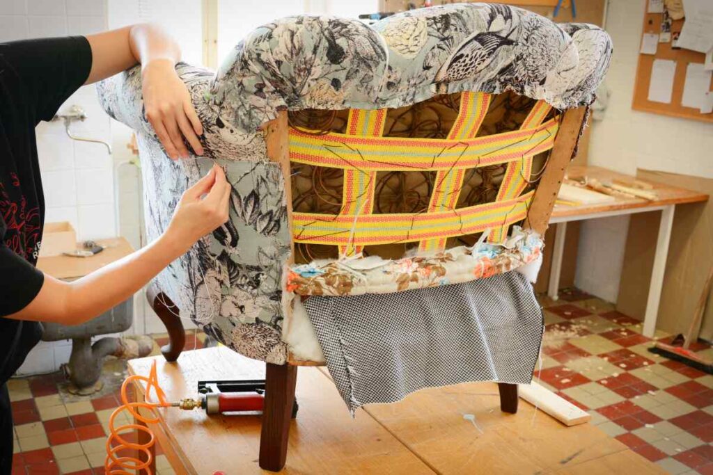 A person adding new upholstery to an old chair