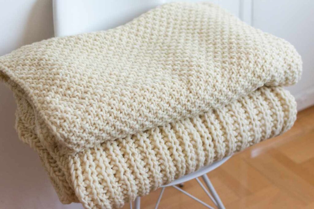 Two crocheted blankets folded on a chair
