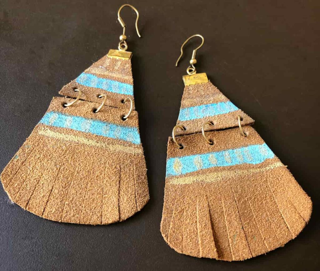 Leather earrings decorated with paint and feathered cuts along with bottom.