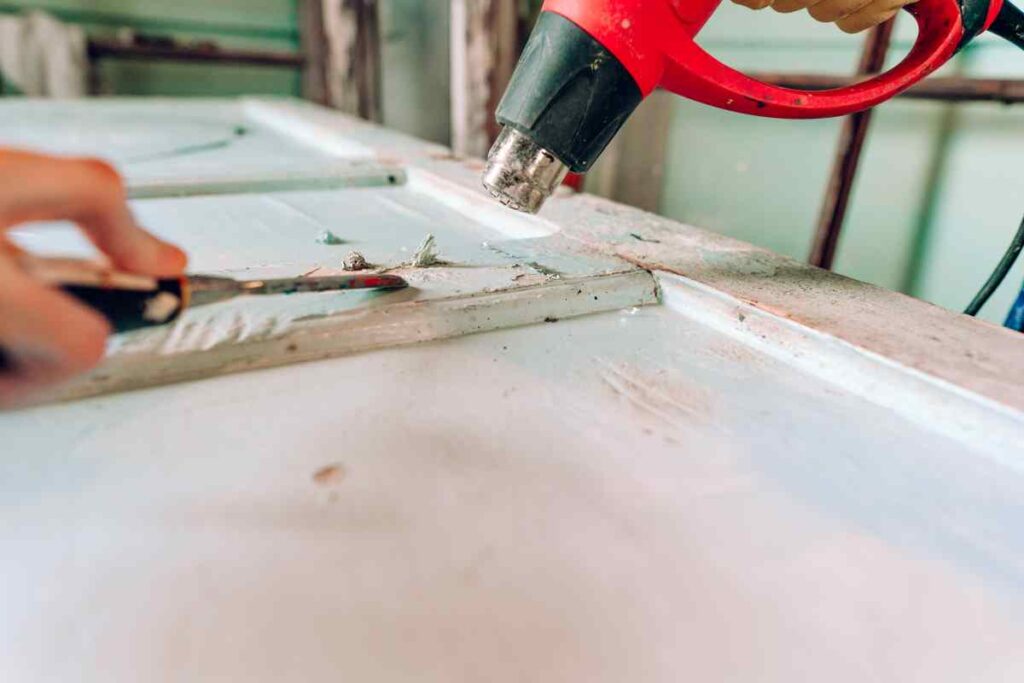 Using a heat gun to remove paint on an old door