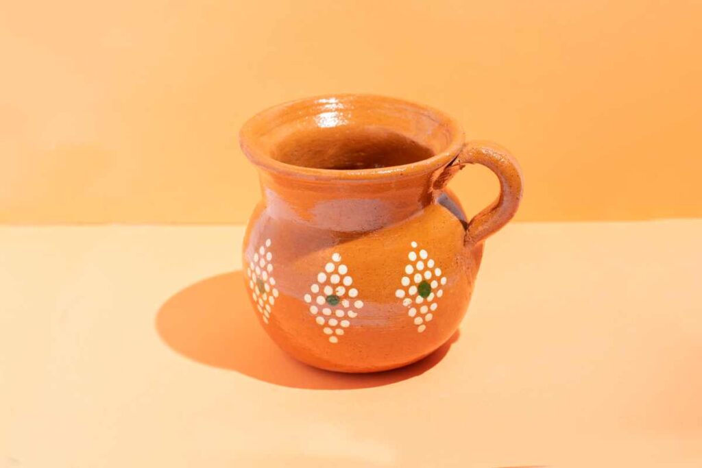 Orange pottery pitcher with diamond designs made out of white polka dots