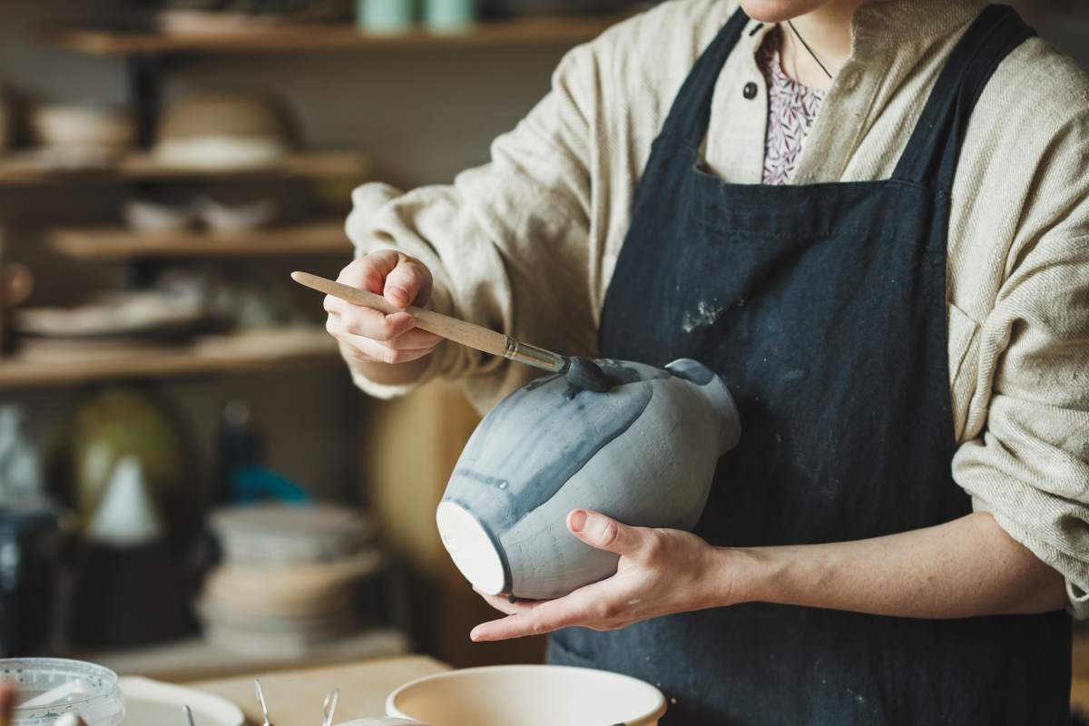 Artist brushing pottery glaze onto a vase. Pottery glaze types