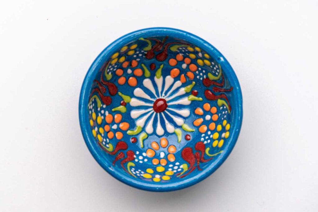 Blue pottery bowl with handpainted flowers in red, yellow, orange, and white