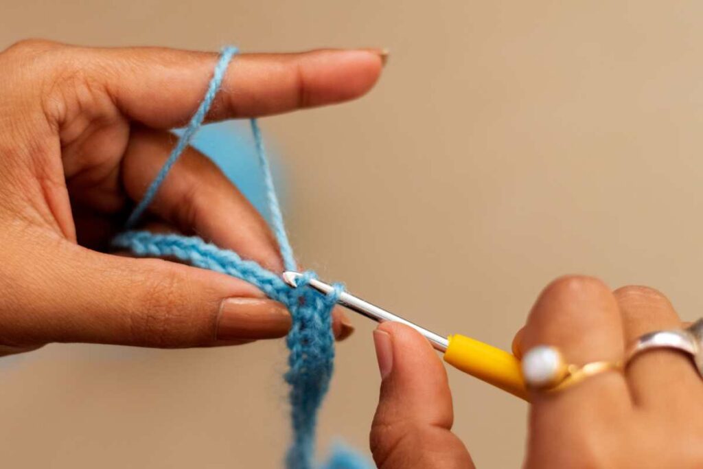 Person's hands showing how to crochet a single stitch row