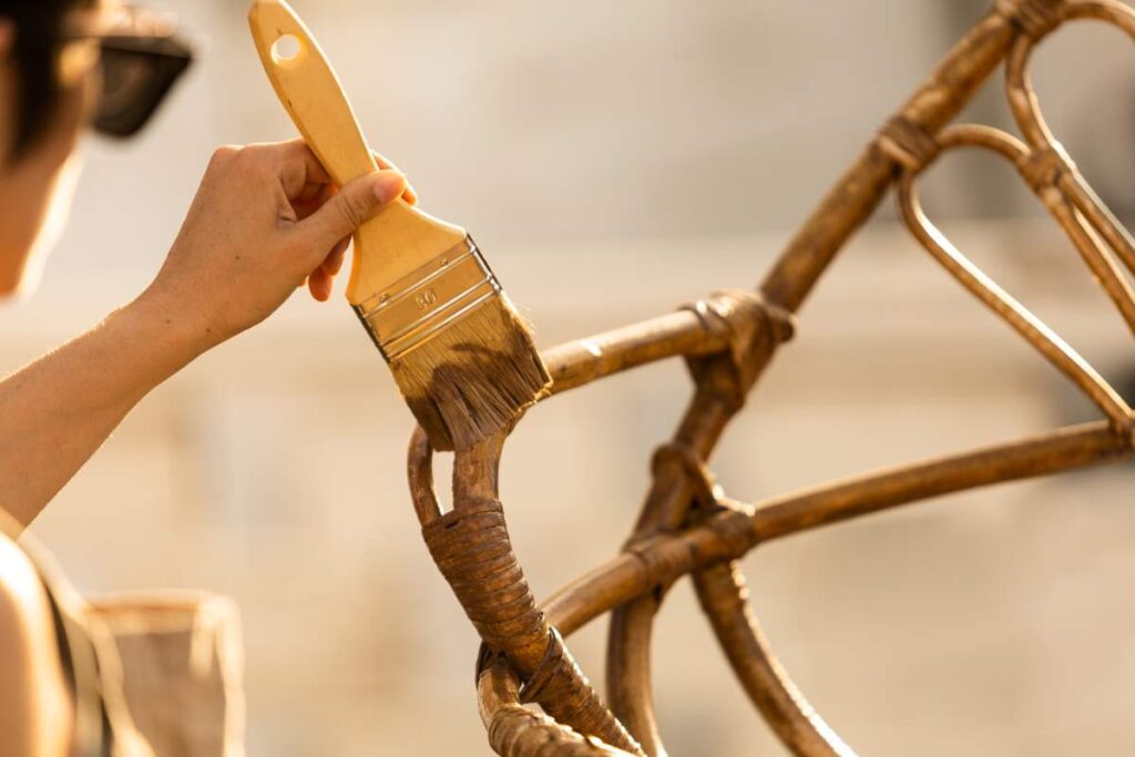 A person staining a wicker chair, one step in repairing wicker furniture