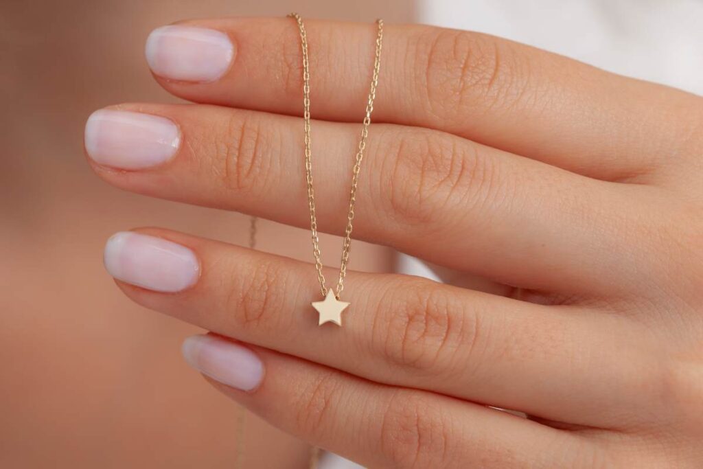 Woman holding a gold star charm necklace
