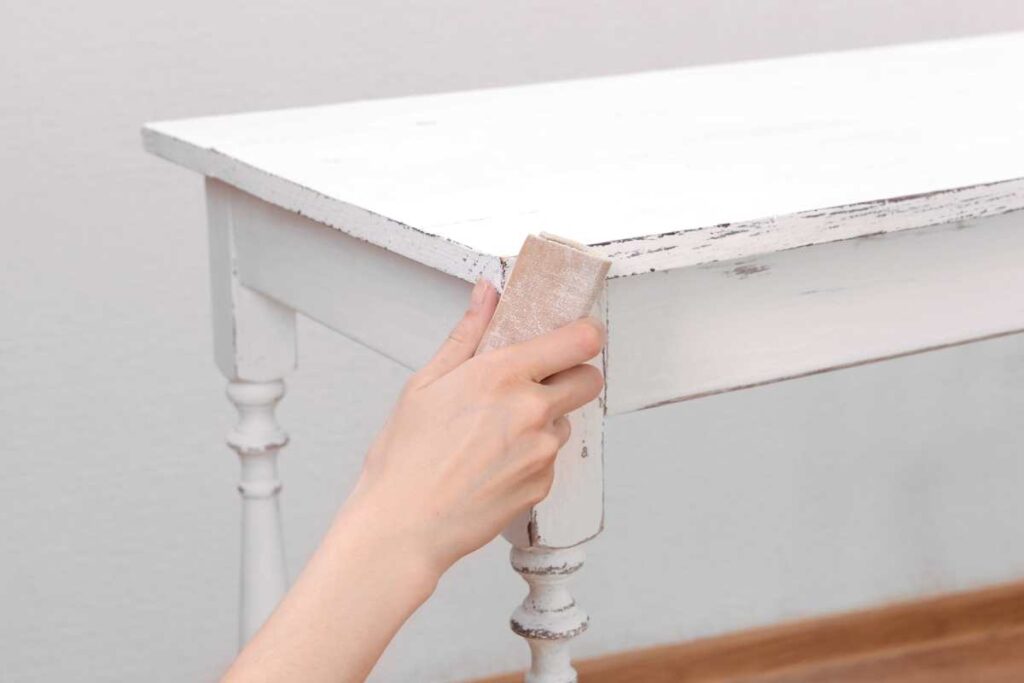 Using a sanding block to sand a white table