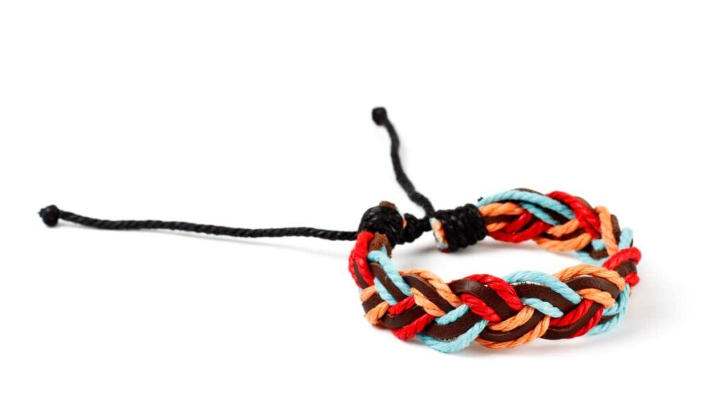 A braided bracelet made with strands of leather and colorful string