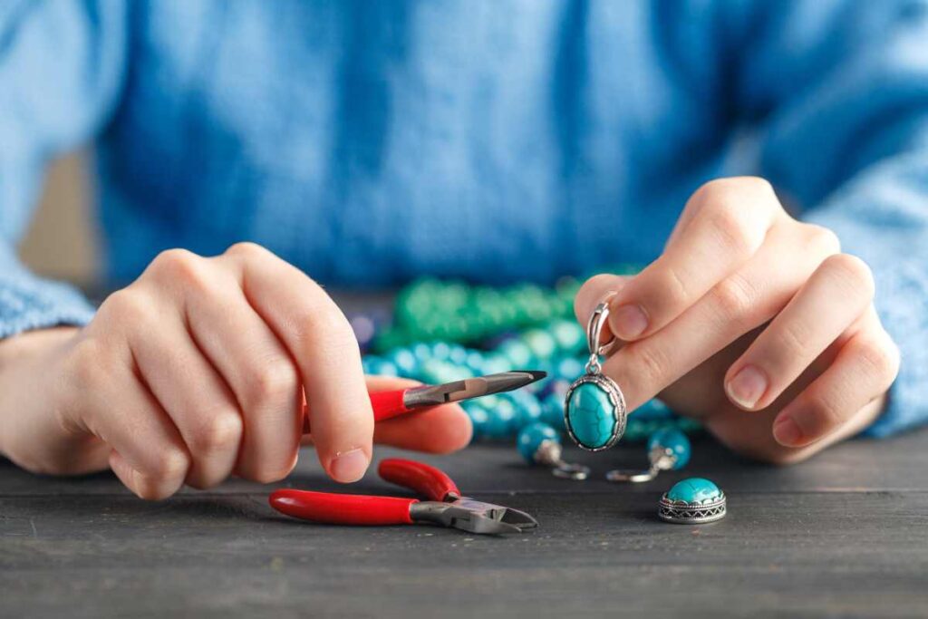 Person making turquoise and silver pendant