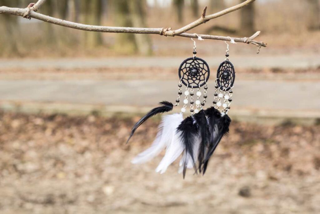A pair of black and white dreamcatcher earrings displayed on a stick