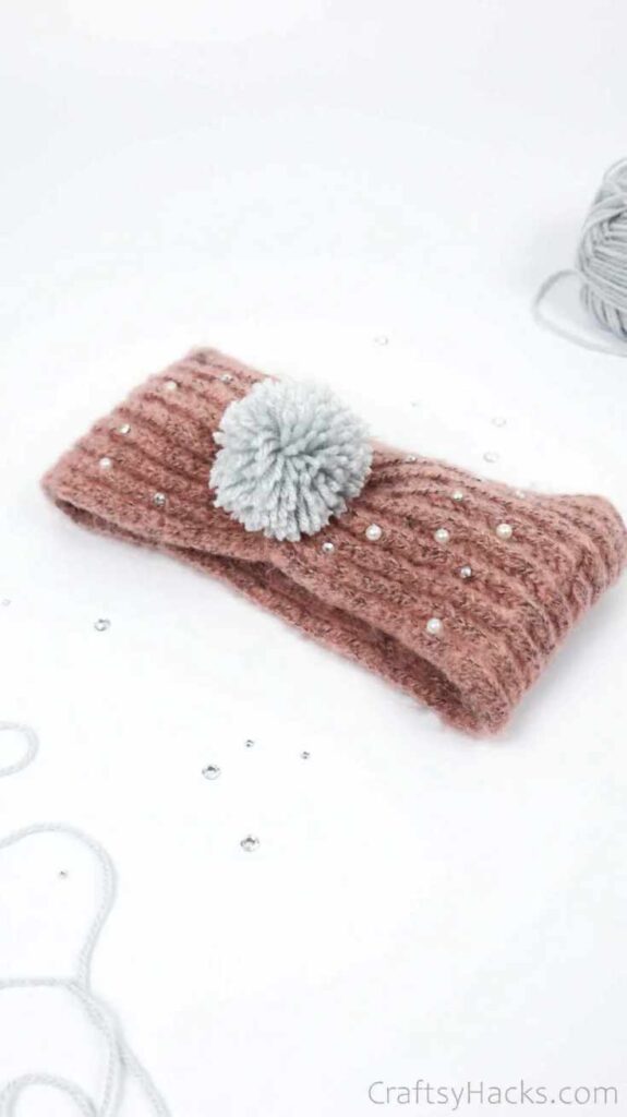 Grey yarn pompom on a brown scarf