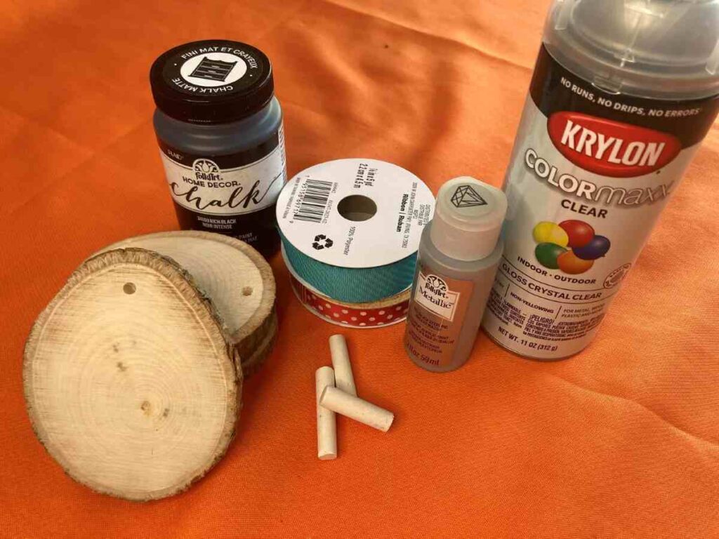Image of supplies needed for painted wood slice ornaments, including ribbons, paint and wood slices