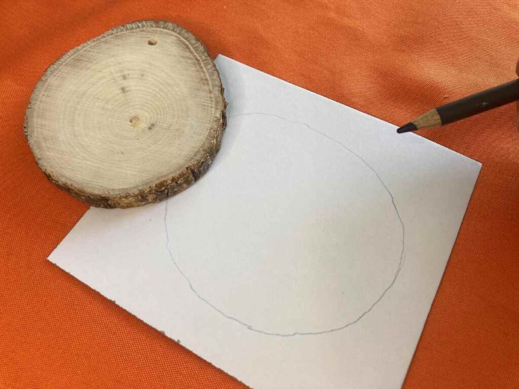 Tracing around a wood slice ornament to make a template for fabric