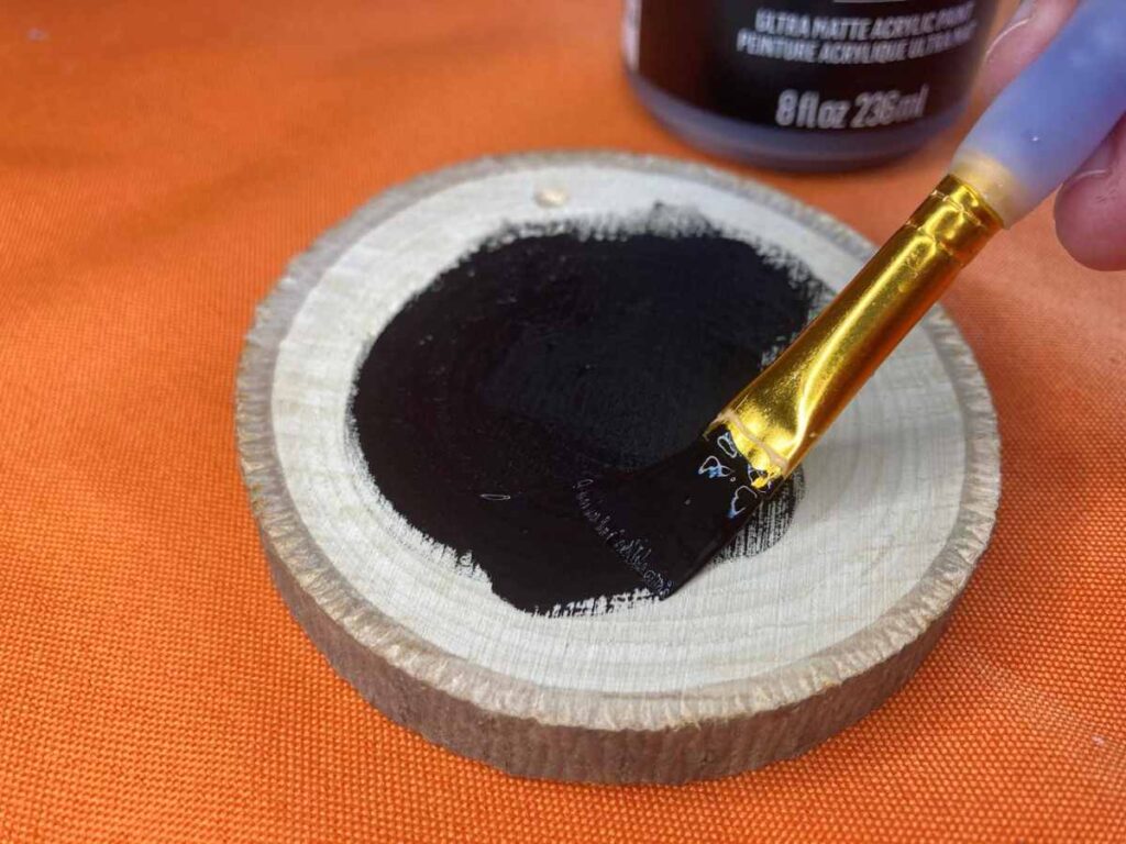 Painting a wood slice ornament with black paint