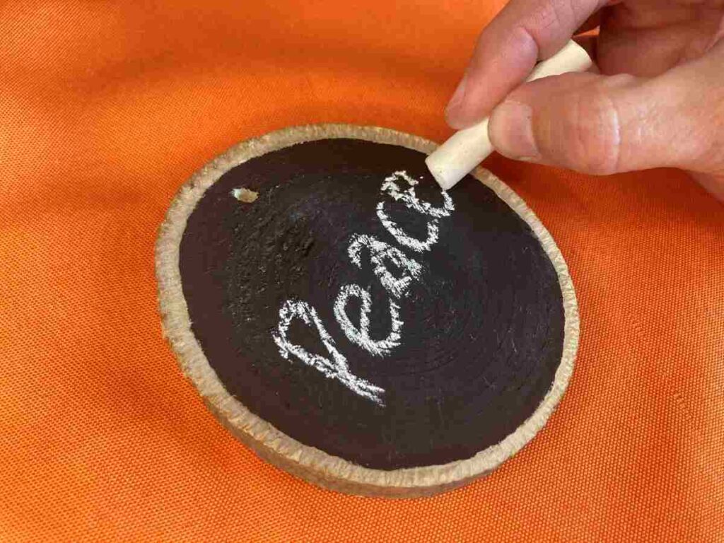Painting the word PEACE on a wood slice ornament